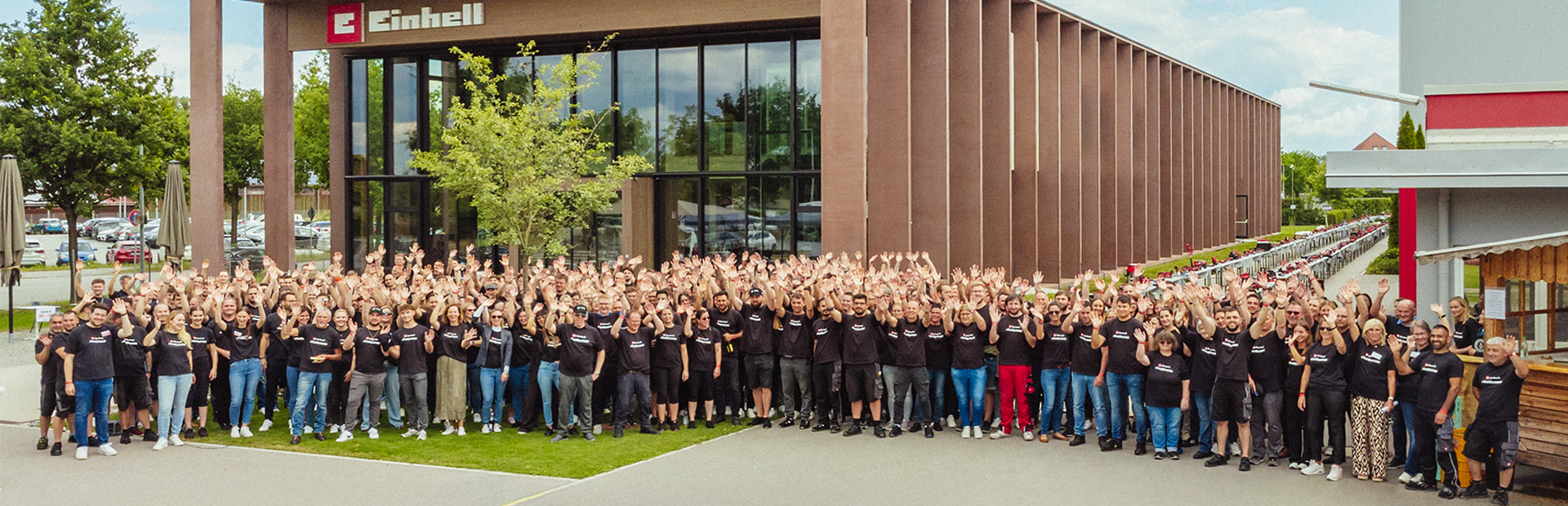 Einhell World: modern company building with Einhell logo and a large group of employees.
