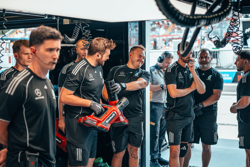 El equipo Mercedes-AMG PETRONAS Formula One Team se encuentra en el garaje. Dos miembros del equipo sostienen sopladoras inalámbricas rojas de Einhell y se preparan para la siguiente acción.