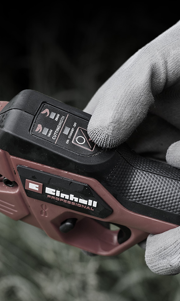 Primer plano de un dispositivo inalámbrico rojo de Einhell con una mano enguantada ajustando su modo.